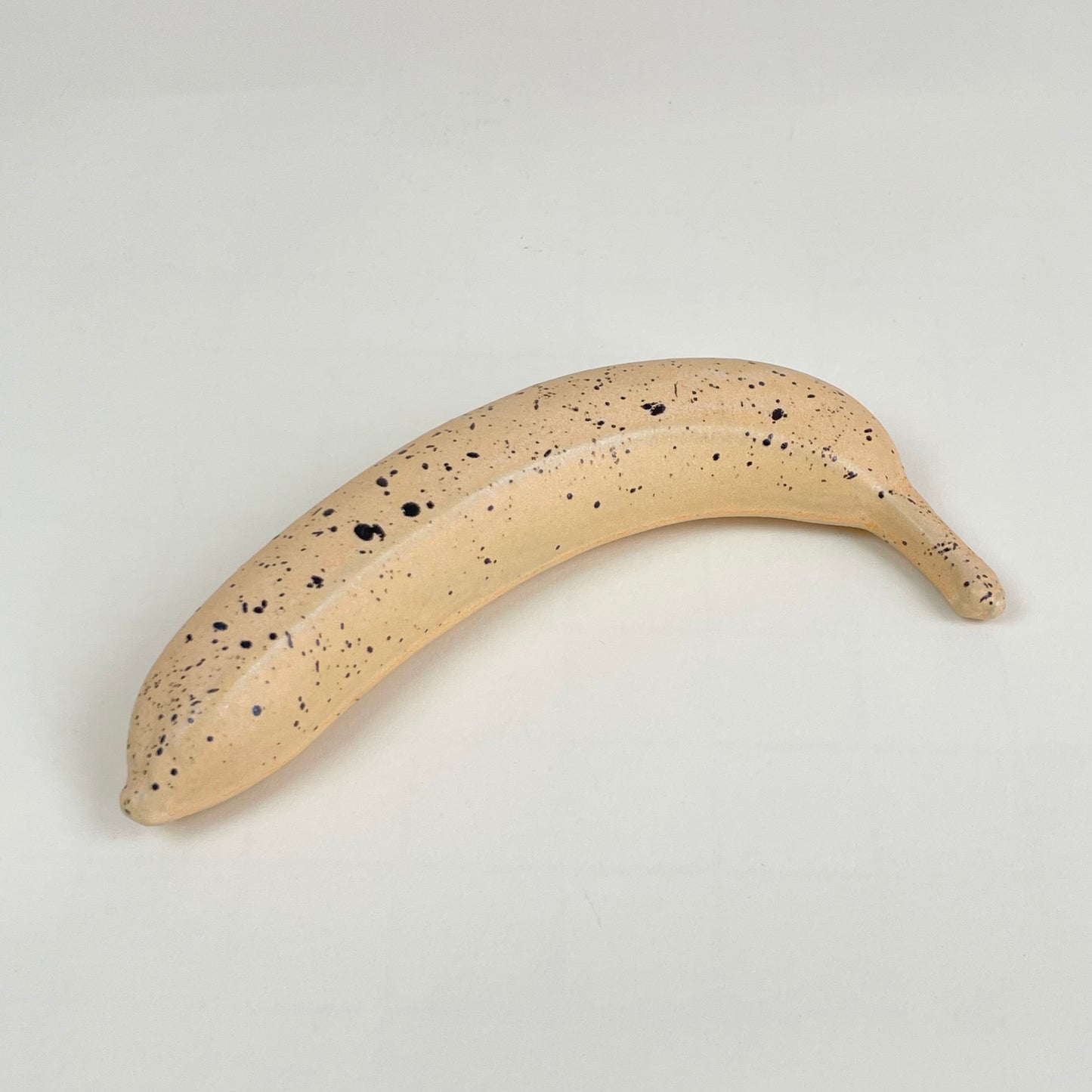 Orange ceramic banana with black speckles by Malwina Kleparska